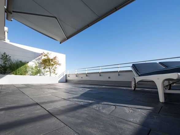 Terrasse sur le toit avec revêtement de sol en ardoise et chaises longues au bord du toit en contre-plongée