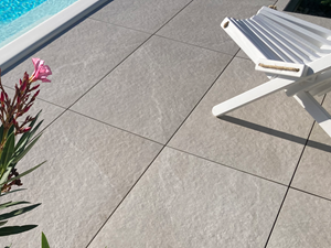 Dallage imitation ardoise Canyon Pearl, chaise longue au bord de la piscine et laurier.