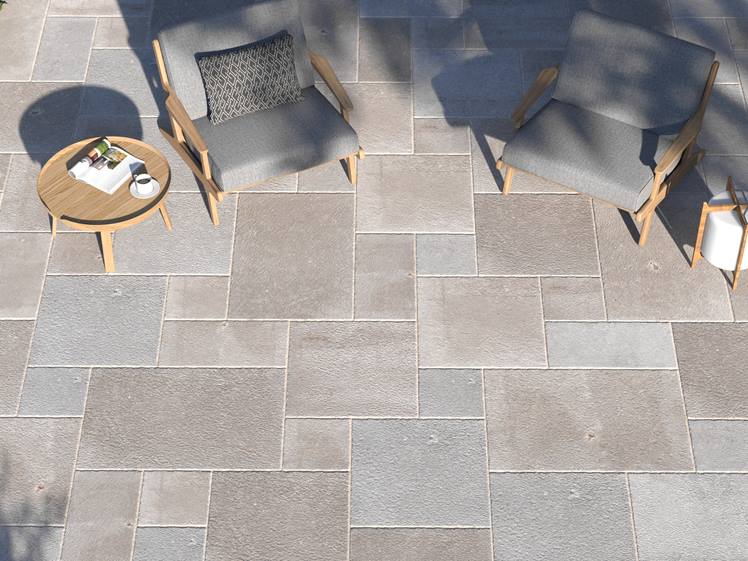 Vue sur le dallage en pierre calcaire Camino Grey avec fauteuils extérieurs et petite table