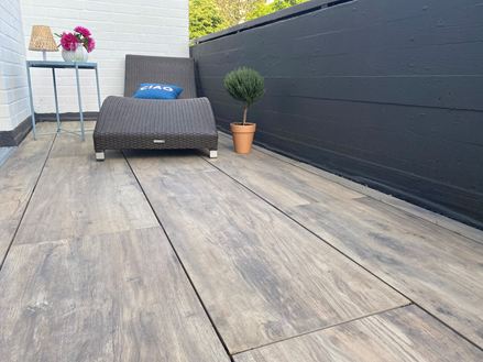 Balcon avec chaise longue et dalles de terrasse en grès cérame imitation bois comme revêtement de sol