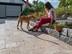 Femme assise sur rebord en pierre avec son chien. Terrasse en dalles de travertin Noce dans les tons bruns.