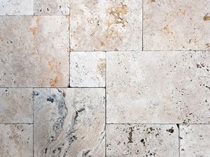 Dalles en travertin vues d'en haut selon la pose en opus romain avec un jeu de couleurs dynamique dans les tons de beige et de brun