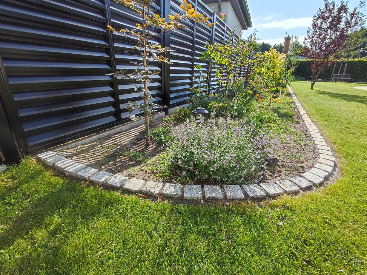 Photo client : les pavés ont été utilisés en tant que bordure de gazon et de massif Pavés aménagés en bordure de massif arrondie