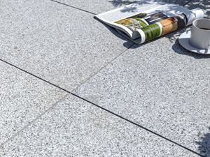 Silver Classico : un dallage moderne à l'aspect poivre et sel Dalles de terrasse en granite Silver Classico avec magazine et tasse de café