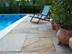 Chaise longue et plantes méditerranéennes sur dalles de pierre naturelle en grès clair directement au bord de la piscine