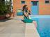 Une petite fille est assise sur la terrasse en grès au bord de la piscine avec son chat dans les bras