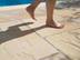 Une personne marche pieds nus sur les dalles claires en grès