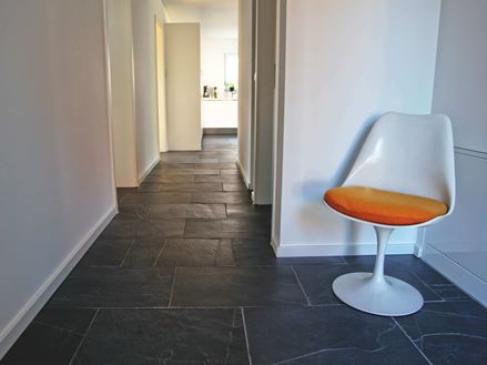 Cliché d'un client : le carrelage en ardoise Black Rustic posé dans un couloir avec un fauteuil en premier plan