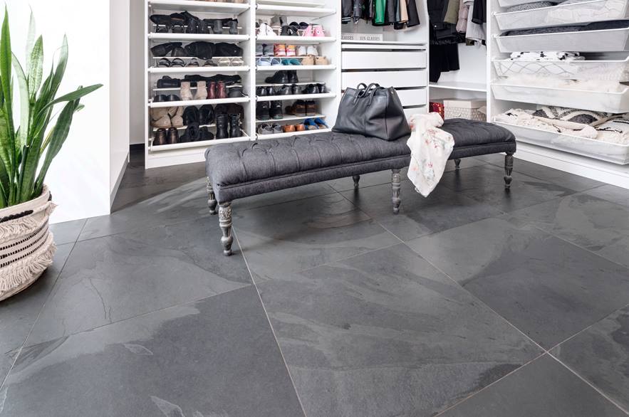 Dressing avec banc gris, armoires blanches ouvertes et carrelage en ardoise Mustang comme revêtement de sol