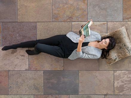 Femme qui lit couchée par terre sur le carrelage en ardoise Peacock Multicolor