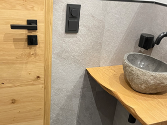 Carrelage mural imitation ardoise Alpine Grey avec lavabo en bois et pierre.