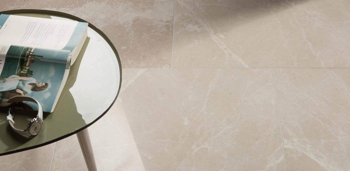 Table ronde avec livre et horloge sur carreau de marbre Burdur Cream