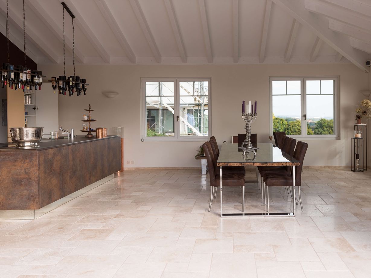 Sol méditerranéen et cuisine moderne : un mélange harmonieux Les carreaux de travertin Light en format opus romain dans une cuisine moderne avec table et îlot