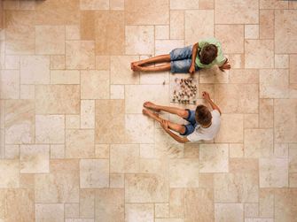 Deux garçons jouent aux échecs sur le carrelage en travertin Light