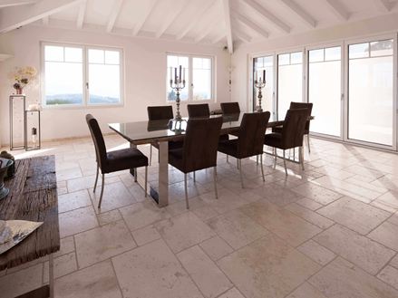 Salle à manger avec table et chaises et au sol un carrelage en travertin Light en format opus romain