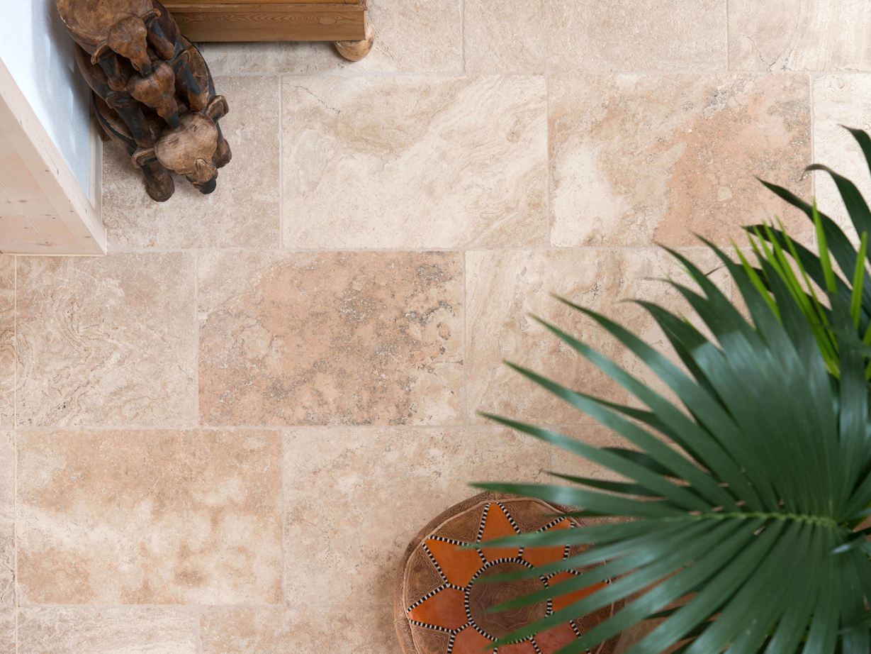 Les veinures à la surface du travertin Rustic font tout son charme Vue de haut sur les carreaux en travertin Rustic, avec mobilier en bois, pouf et palmier