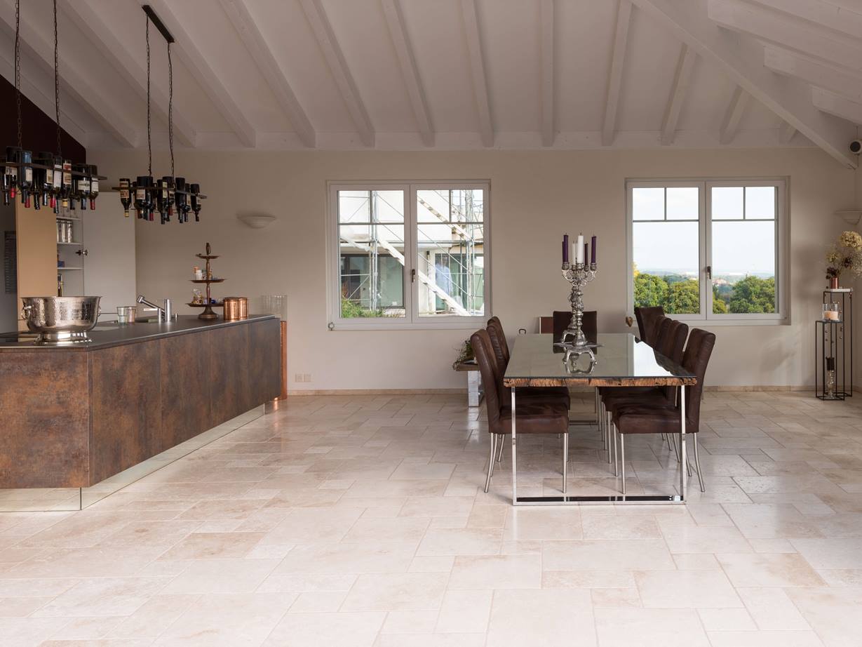 Sol méditerranéen et cuisine moderne : un mélange harmonieux Les carreaux de travertin Light en format opus romain dans une cuisine moderne avec table et îlot