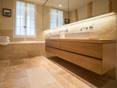 Une salle de bain en travertin deux robinet sur la droite une baignoir et une fenetre