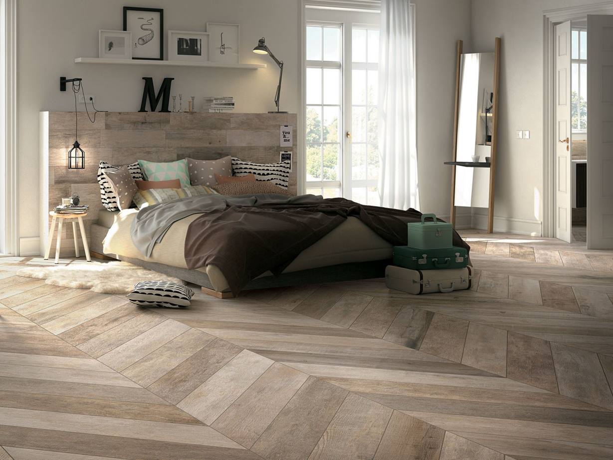 chambre avec grand lit et carrelage en pierre fine de couleur brun-beige comme revêtement de sol