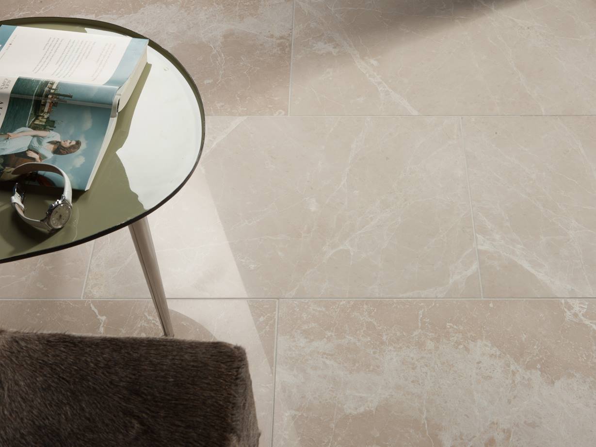 Ce marbre décliné sous de douces nuances représente une élégance intemporelle ! Une table ronde avec un livre et une montre sur le carrelage en marbre Burdur Cream