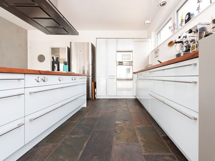 Cuisine moderne avec meubles blancs et ardoise colorée comme revêtement de sol