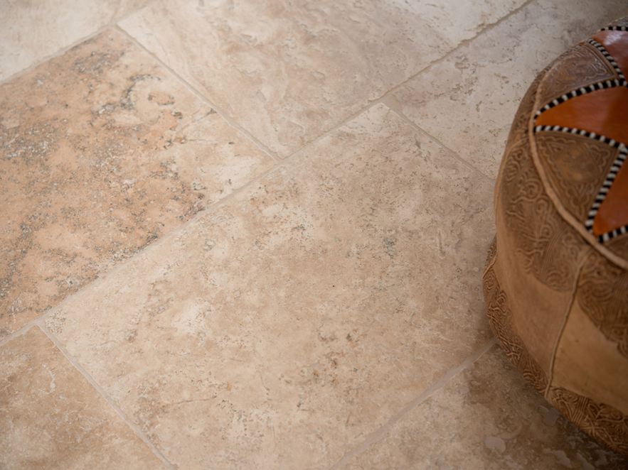 En détail : carrelage Rustic, en travertin tambouriné, à droite un pouf marocain