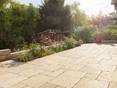terrasse en travertin medium select avec beau jardin et personne assise