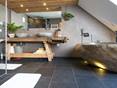 salle de bain avec baignoire en pierre, meubles en bois et carrelage en ardoise