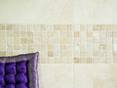 Cette mosaïque en travertin ne passe pas inaperçue. Mosaïque en travertin, entouré de revêtement mural travertin avec coussin violet