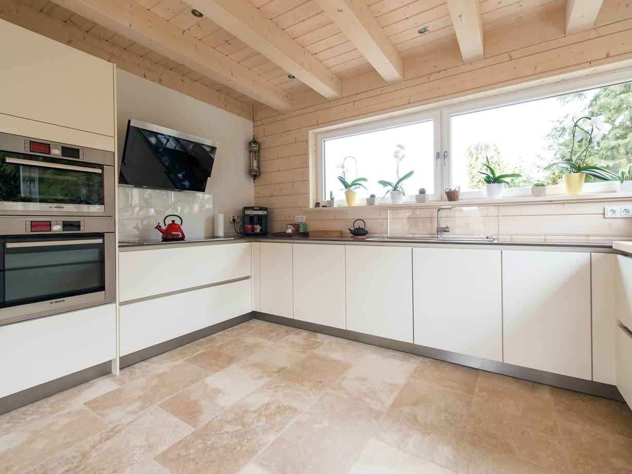 Le travertin Rustic se marie avec des meubles blancs. Des éléments de cuisine blancs et un sol en travertin Rustic