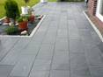 Une terrasse avec des plantes et un sol en ardoise Black Rustic, à droite il y a un mur extérieur