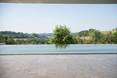en premier plan le travertin Line et en derrière une piscine avec de la verdure