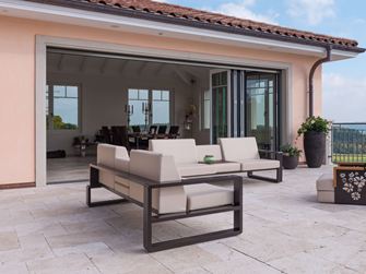 Terrasse en travertin Light avec du mobilier moderne canapé fauteuils et face à la maison ouverte