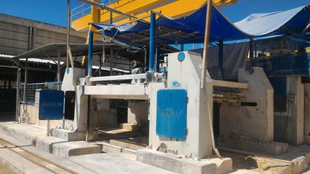 Eine Gattersäge zerteilt einen rohen Steinblock in sog. "Tranchen"