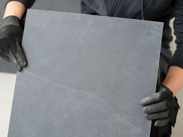 Un carreleur tient un carreau d'ardoise dans la caméra